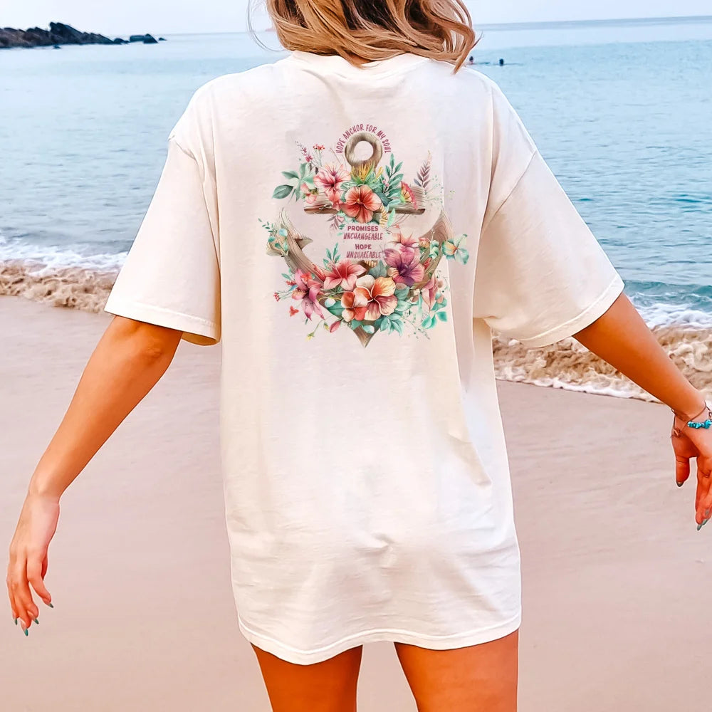 A person standing on the beach wearing a Be Still and Know Hope Anchor Floral Shirt, adorned with Hawaiian flowers on the back.