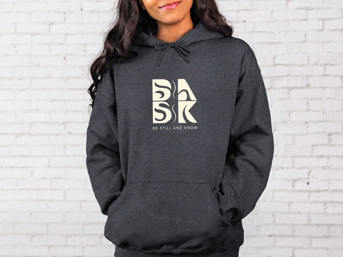 A gray Blessed Beginnings Hoodie In Dark Heather with a white Be Still and Know Logo on it.