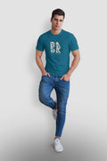 A man wearing a teal Be Still and Know Christian t-shirt and jeans.