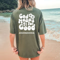 Person standing on a beach wearing a Be Still and Know God Means It For Good Shirt, colored green with the text 