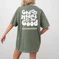 A person wearing a Be Still and Know God Means It For Good Shirt in green with the phrase 