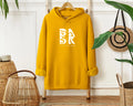 A Golden Coast In Hoodie In Gold with the Be Still and Know Logo on it.