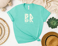 A turquoise Aloha Maluhia Tee In Heather Mint with the word Be Still and Know on it, ideal for Christian clothing or Christian apparel.