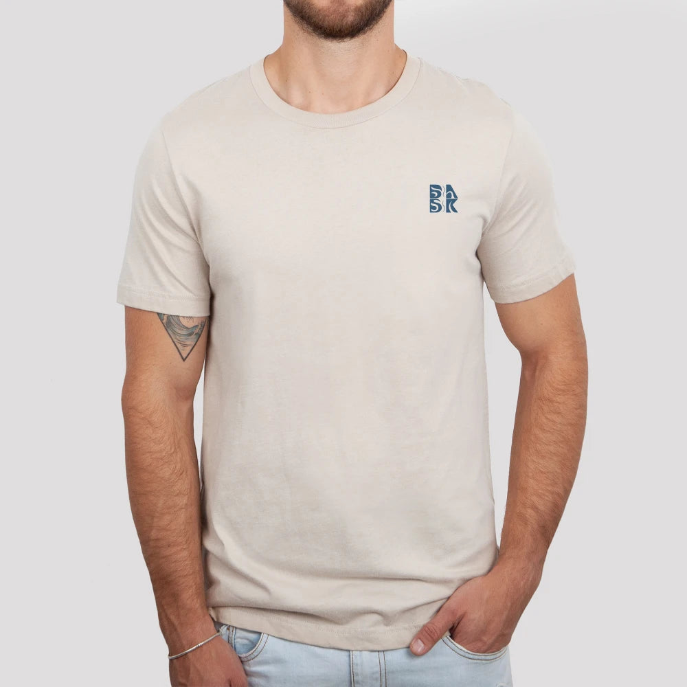Man wearing beige t-shirt with nautical "Be Still and Know" Hope Anchors Shirt on the back, symbolizing unshakeable hope.