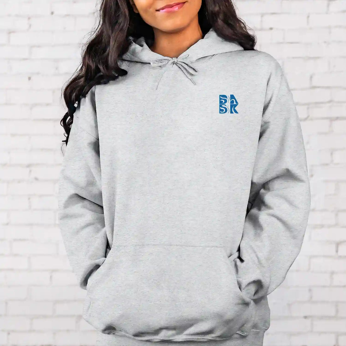 A Hawaiian woman confidently rocks her Be Still and Know Kupa'a Tide Hoodie in grey, showcasing unwavering faith.
