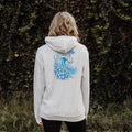 The back of a woman wearing a Be Still and Know Kupa'a Tide Hoodie with a blue wave design and unwavering faith.