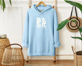 A Coastal Calm Hoodie in Light Blue with the Be Still and Know logo on it.