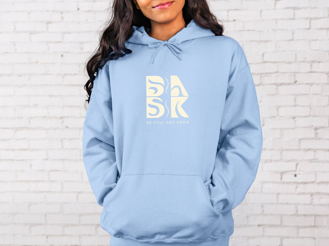 A Coastal Calm Hoodie in Light Blue with a white Be Still and Know logo on it.