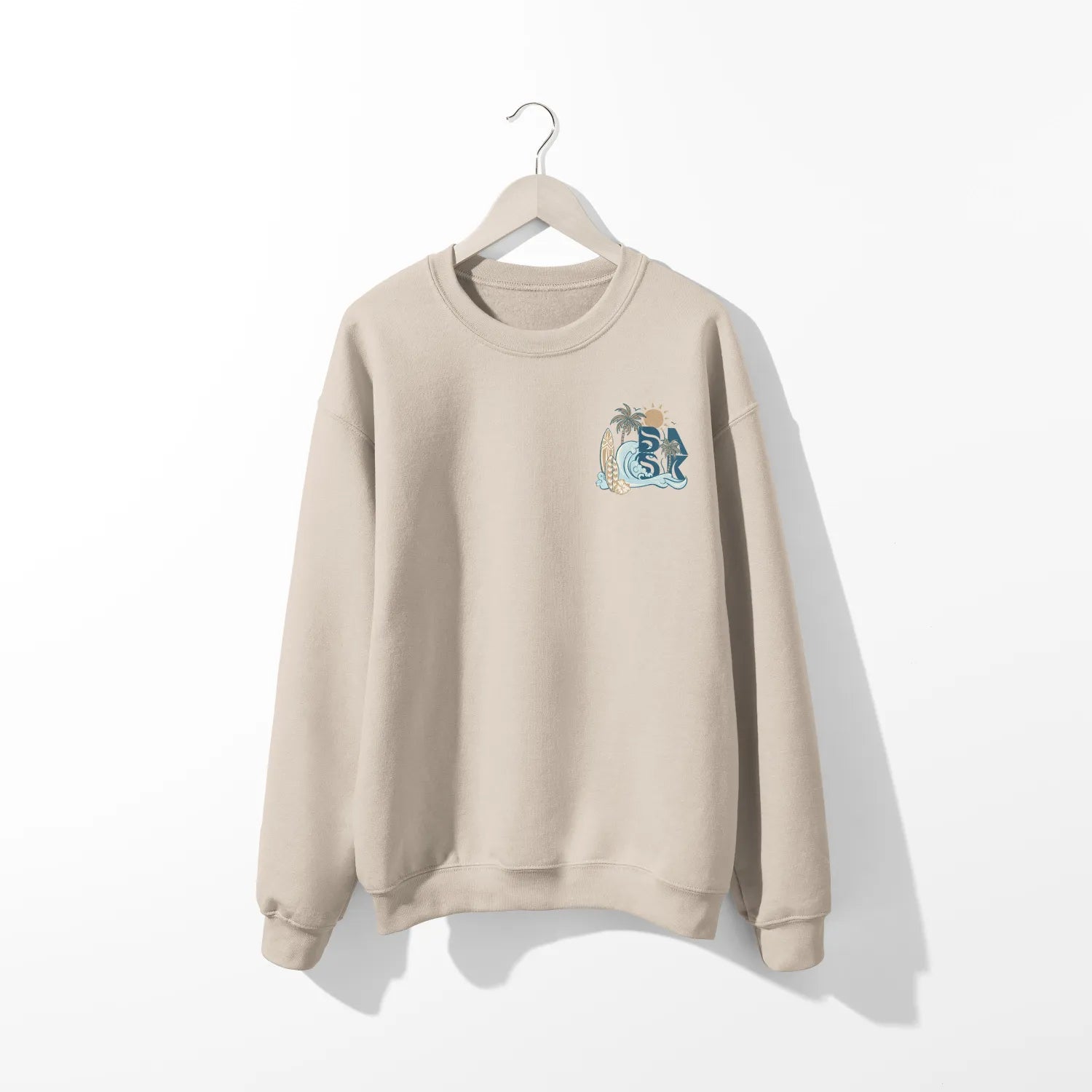 A beige Nalu o ka Mana (Waves of Faith) sweatshirt with a blue and white owl on it, featuring the Be Still and Know logo.