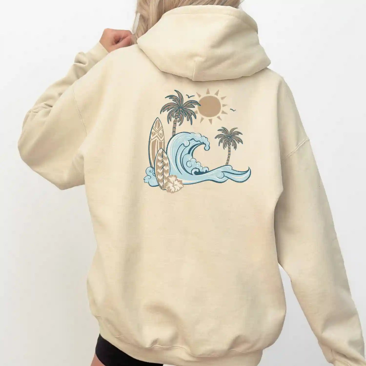 A woman wearing a hoodie with palm trees, representing the Nalu o ka Mana (Waves of Faith) Hoodie by Be Still and Know.