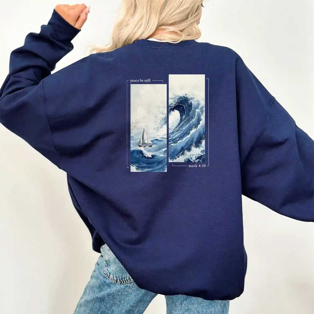 A woman wearing a navy Peace Be Still Sweatshirt with the Be Still and Know logo.