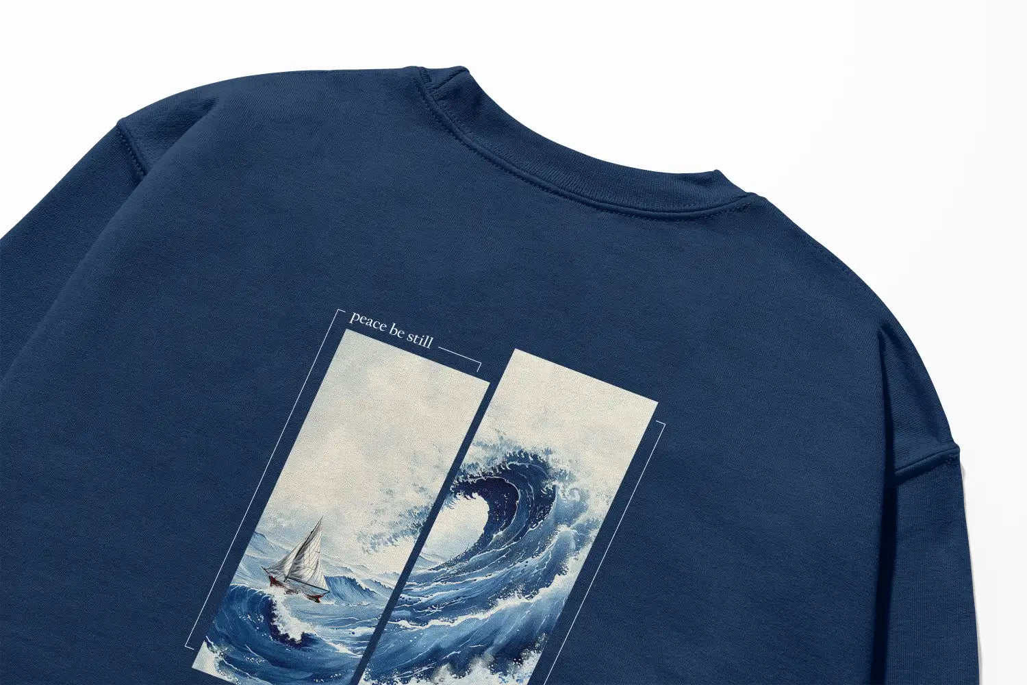 A Peace Be Still Sweatshirt with an image of a wave and a sailboat featuring the Be Still and Know Logo.
