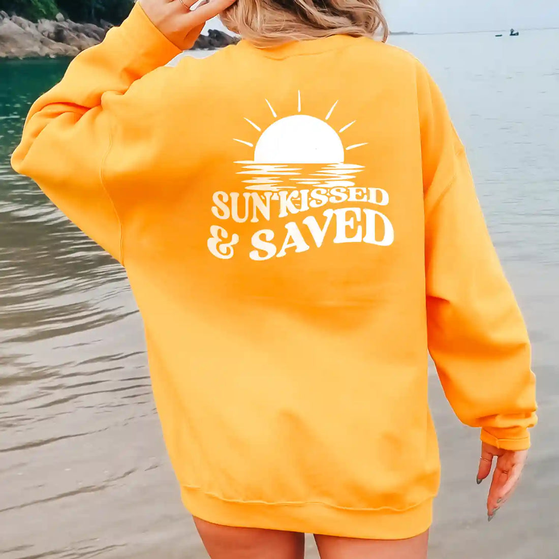A woman wearing a Sunkissed & Saved Sweatshirt by Be Still and Know with the word "sunstruck" prominently displayed.