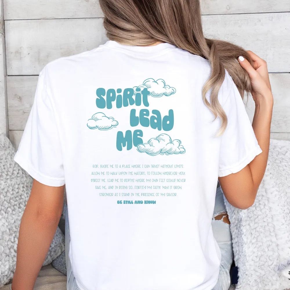 A person from behind, wearing a white "Spirit Lead Me" Shirt by Be Still and Know with text and cloud illustrations that reads "Spirit Lead Me" along with a message of trust in Savior and inspiration.