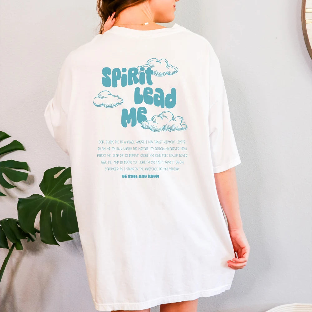 Woman wearing an oversized white Spirit Lead Me shirt with the phrase "Spirit Lead Me" printed on the back, surrounded by cloud graphics and trust in Savior text by Be Still and Know.