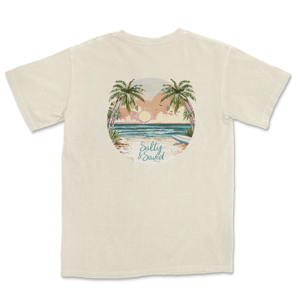 Be Still and Know "Salty & Saved" shirt with a circular tropical beach graphic featuring palm trees and sunset, and the words "salty & sweet" at the bottom.