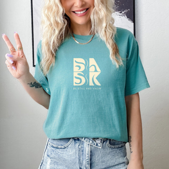 A Aloha Tee In Seafoam with the word "bak" and the BSAK logo, perfect for Christian Clothing enthusiasts.