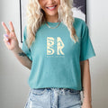 A blonde woman wearing the Be Still and Know Aloha Tee In Seafoam.