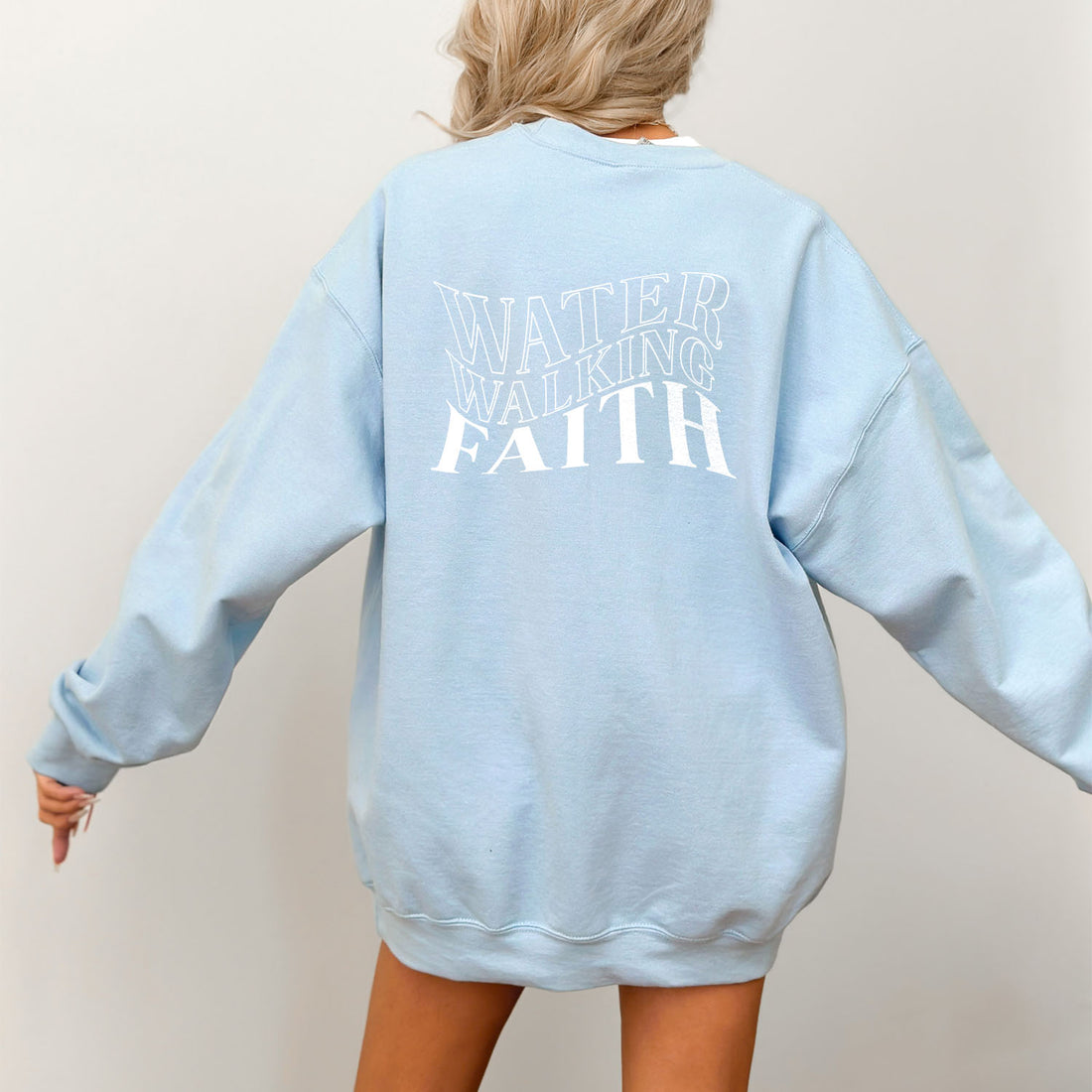 A woman of faith confidently donning a Water Walking Faith Sweatshirt by Be Still and Know.